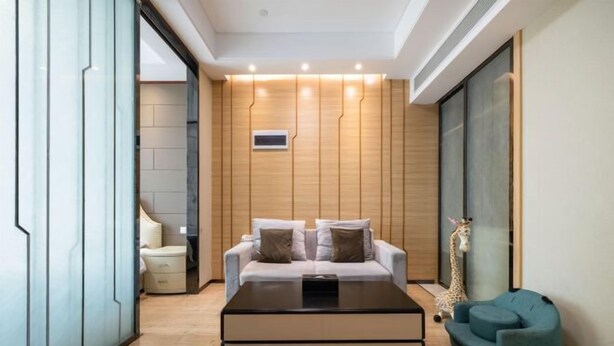 A modern living room with a sofa, a coffee table, a giraffe decoration, and a blue chair. - Sweetome Boutique Apartment (Yangzhou Railway Station Jinghua City) (Yangzhou)