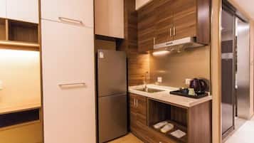 A compact kitchen with a refrigerator, sink, and wooden cabinetry.