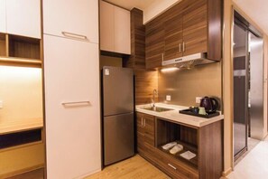 Una cocina compacta con refrigerador, lavabo y armarios de madera.