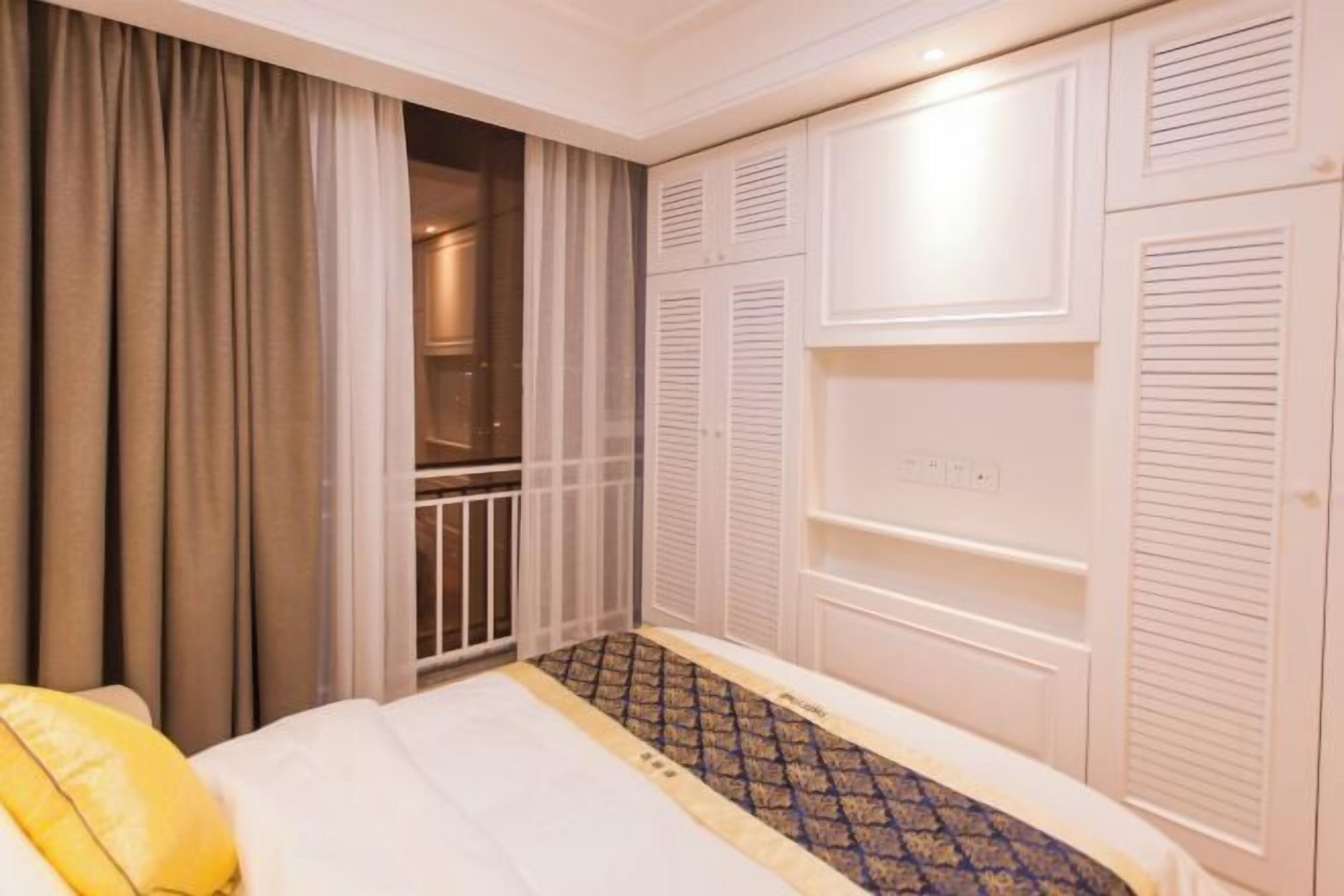 A bedroom with a bed, a wardrobe, and a window with curtains.