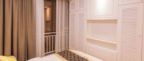 A bedroom with a bed, a wardrobe, and a window with curtains.