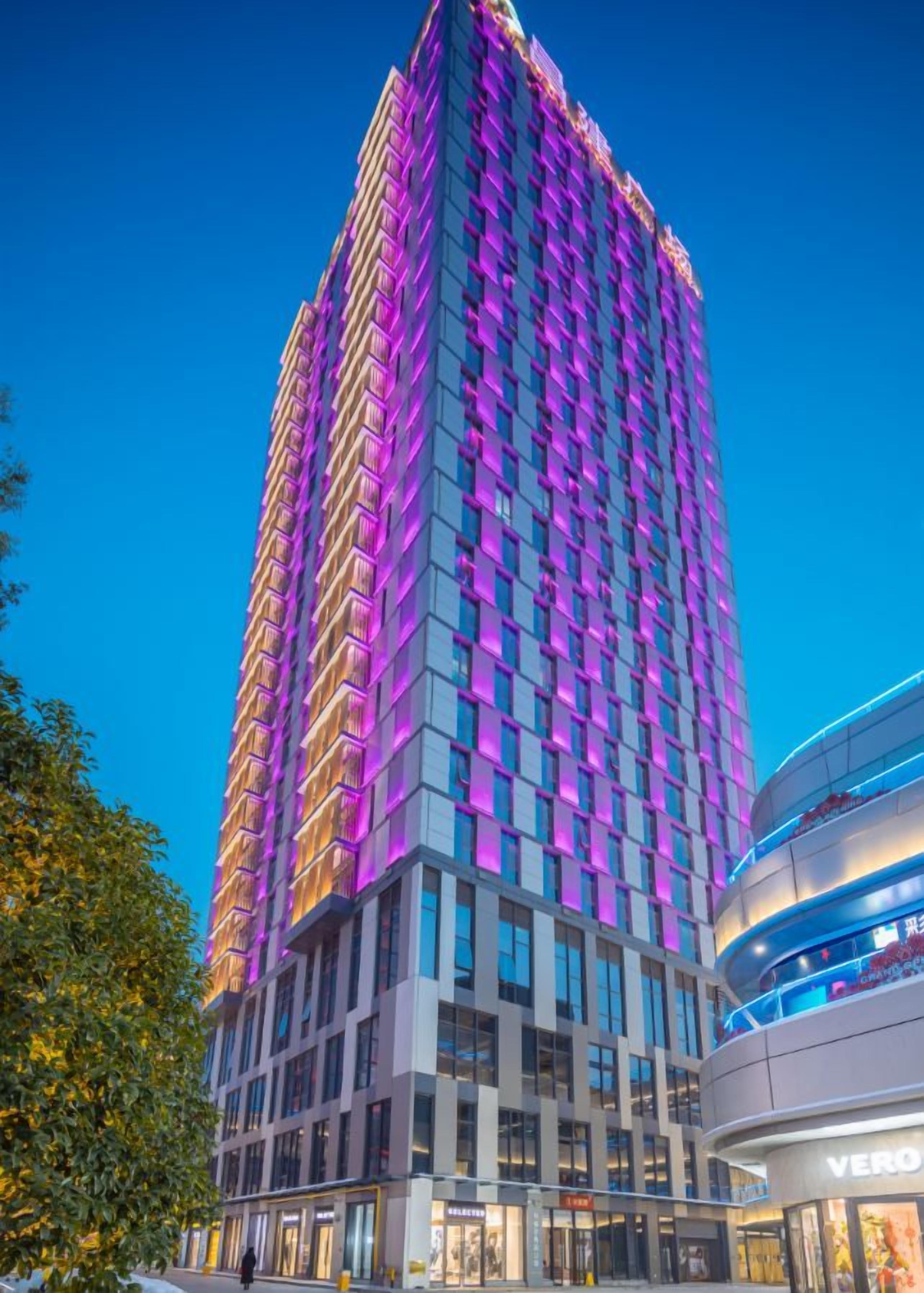 Ein hoch aufragendes Hotel mit modernem Design, das durch eine markante vertikale Struktur und einen unteren Bereich mit sichtbaren Geschäftsflächen gekennzeichnet ist.