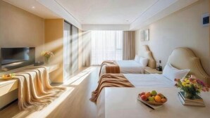 A hotel room with two beds, a TV, a bedside table with a bowl of fruit, and a window with curtains. - Sweetome Boutique Apartment (Yangzhou Railway Station Jinghua City) (Yangzhou)