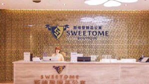 A reception desk with a logo and name "SWEETOME BOUTIQUE" in both English and Chinese. - Sweetome Boutique Apartment (Yangzhou Railway Station Jinghua City) (Yangzhou)