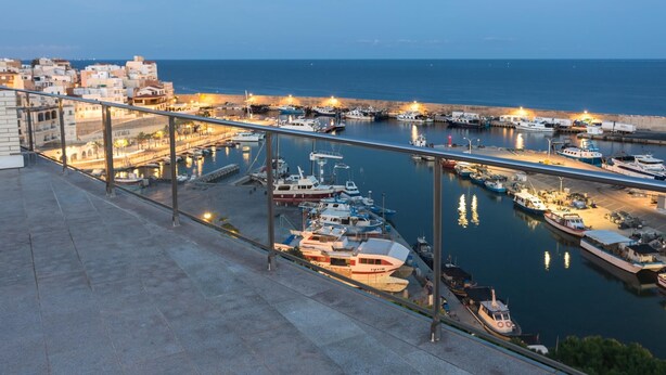 Un puerto deportivo con barcos amarrados, un puente y edificios al fondo.