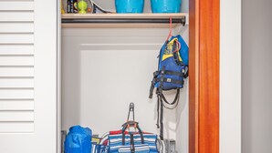 A storage closet with shelves holding blue buckets, a blue backpack, and a striped bag.