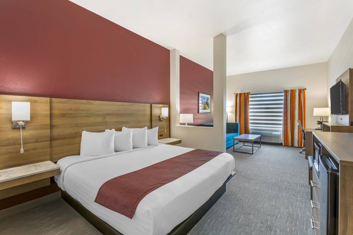 A hotel room with a large bed, a desk, a chair, and a television.