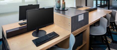 A modern office space with a wooden desk, two computer monitors, a keyboard, and two chairs.