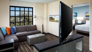 Una habitación de hotel con sofá, televisión, escritorio, lámpara y cama.
