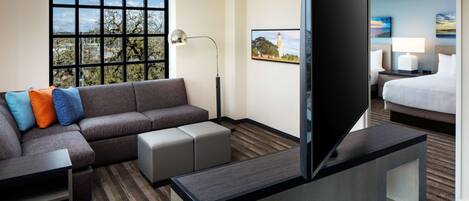 Una habitación de hotel con sofá, televisión, escritorio, lámpara y cama.