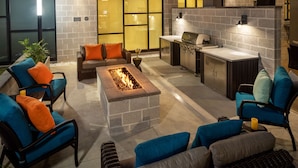 Un patio al aire libre con asientos, una chimenea y una zona de cocina.