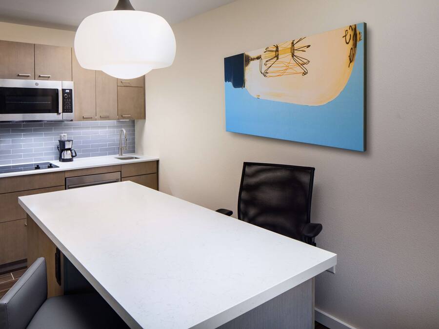 A modern kitchen with a white countertop, stainless steel microwave, and a coffee maker.