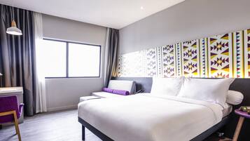 A modern hotel room with a large bed, a desk, and a window with curtains.