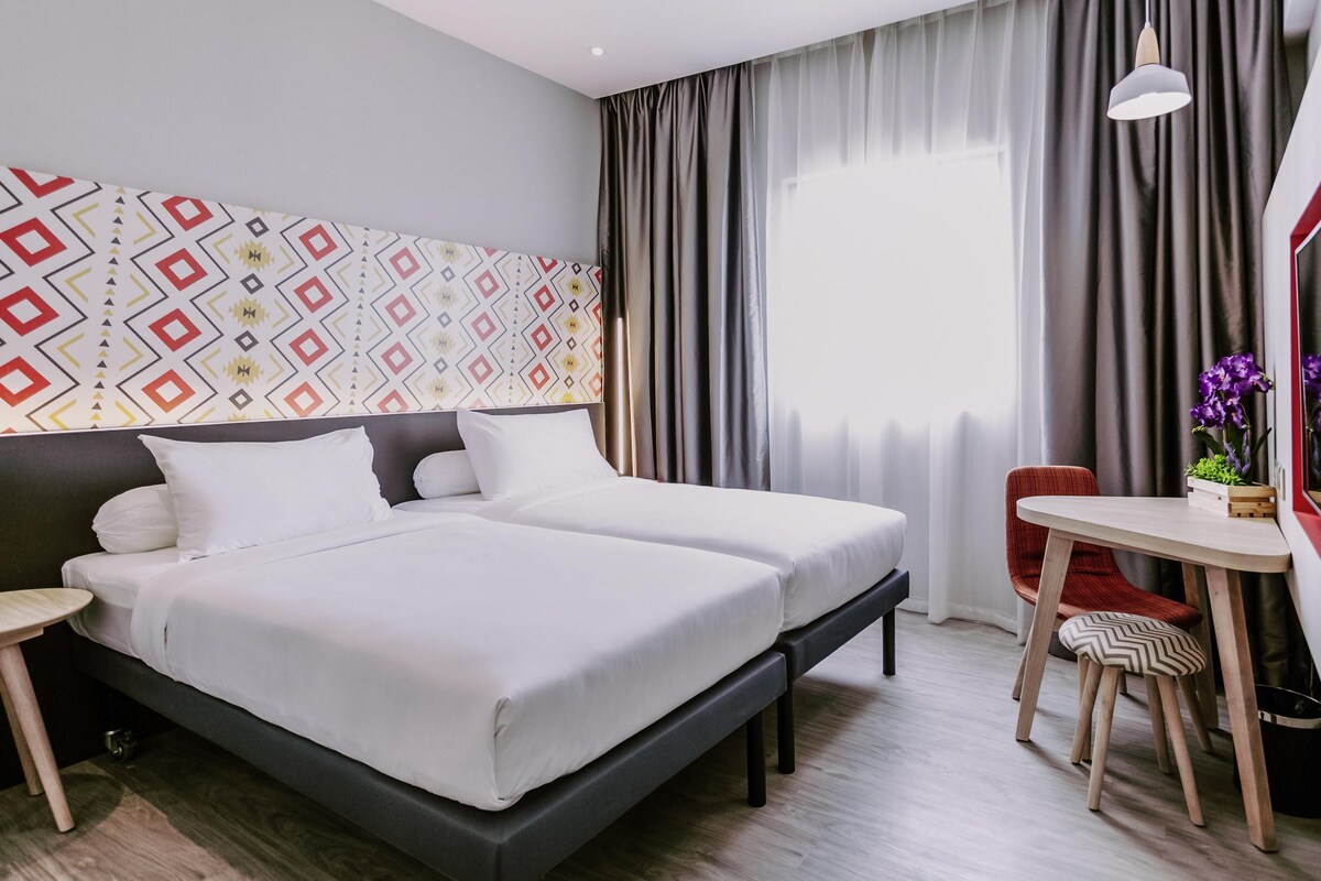Une chambre d’hôtel moderne, dotée d’un grand lit, d’un bureau et d’une chaise.