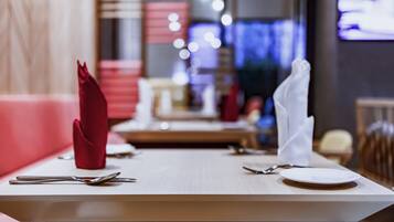 A restaurant setting with a table set for two, including cutlery and napkins.
