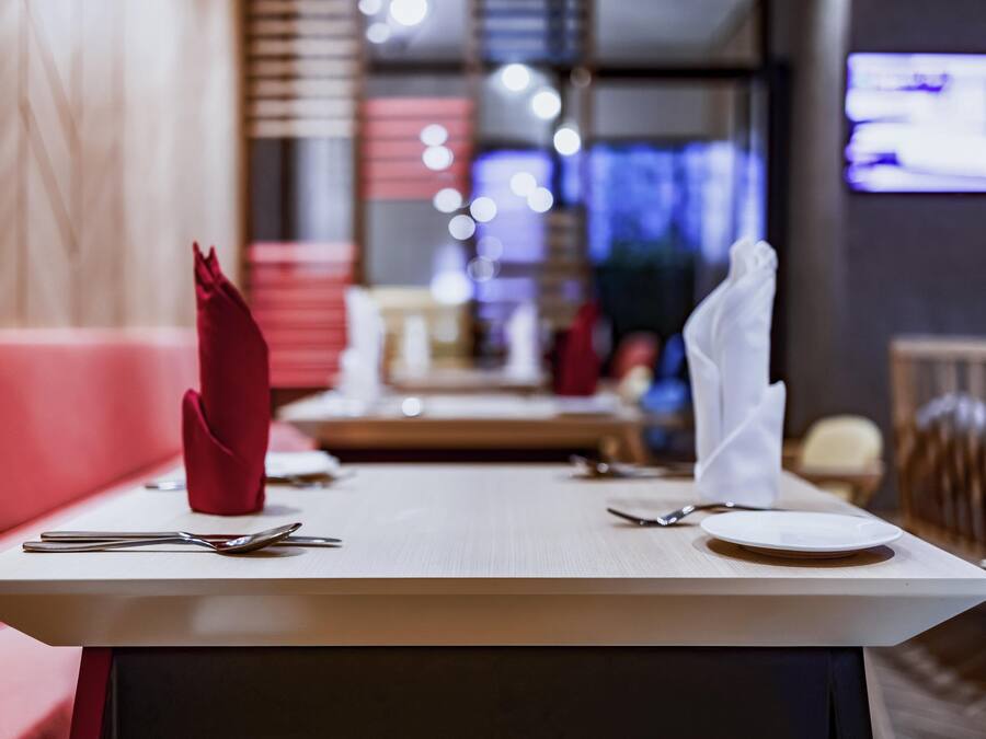 A restaurant setting with a table set for two, including cutlery and napkins.