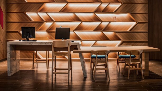 Un espacio de oficina moderno con un escritorio de madera, dos sillas y un monitor de computadora.