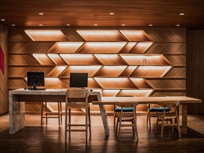Un espacio de oficina moderno con un escritorio de madera, dos sillas y un monitor de computadora.