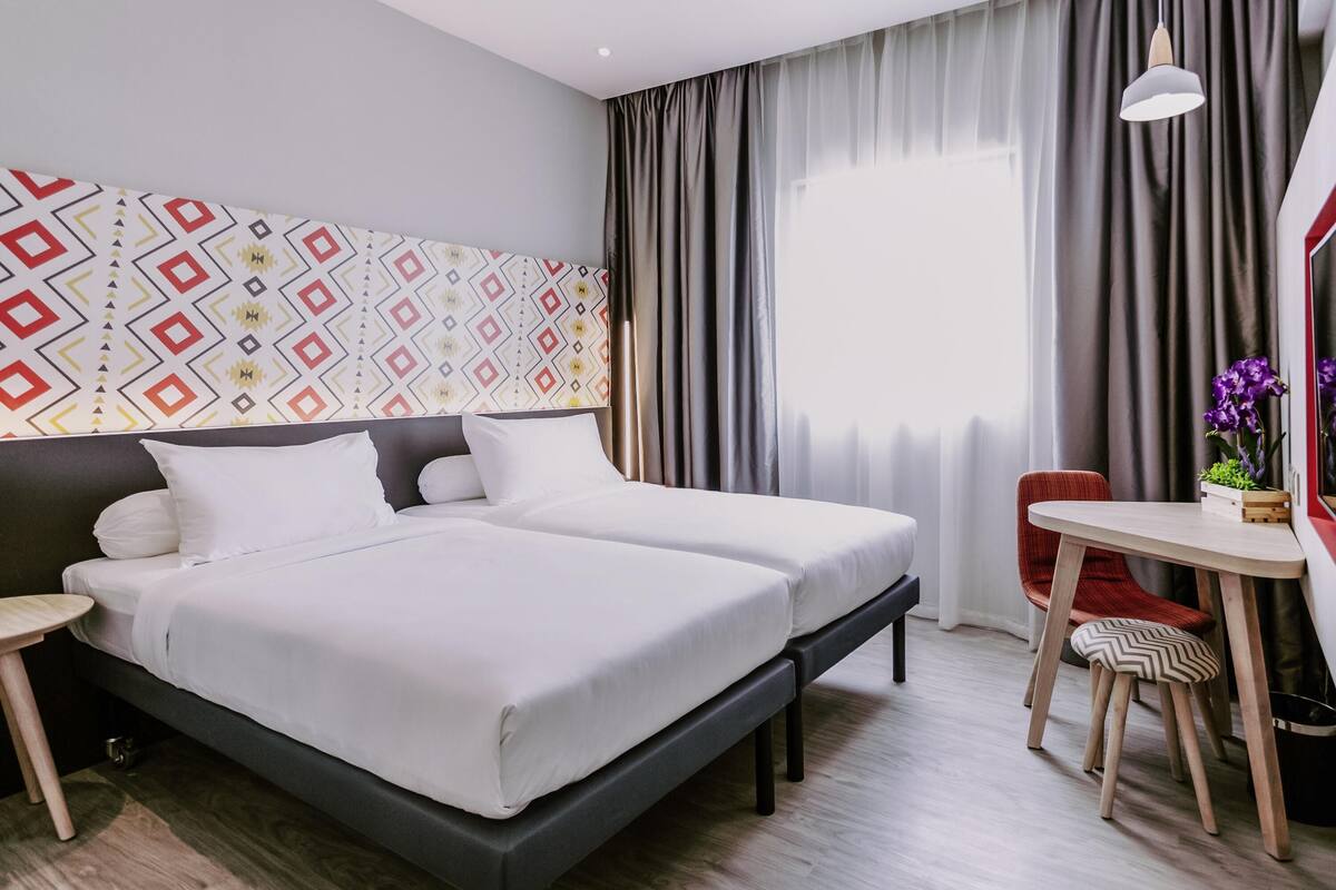 Una habitación de hotel moderna con una cama grande, un escritorio y una silla.