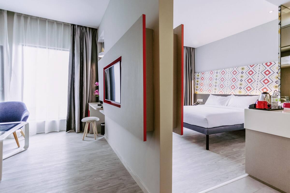 Una habitación de hotel moderna con cama, escritorio, silla y televisión.