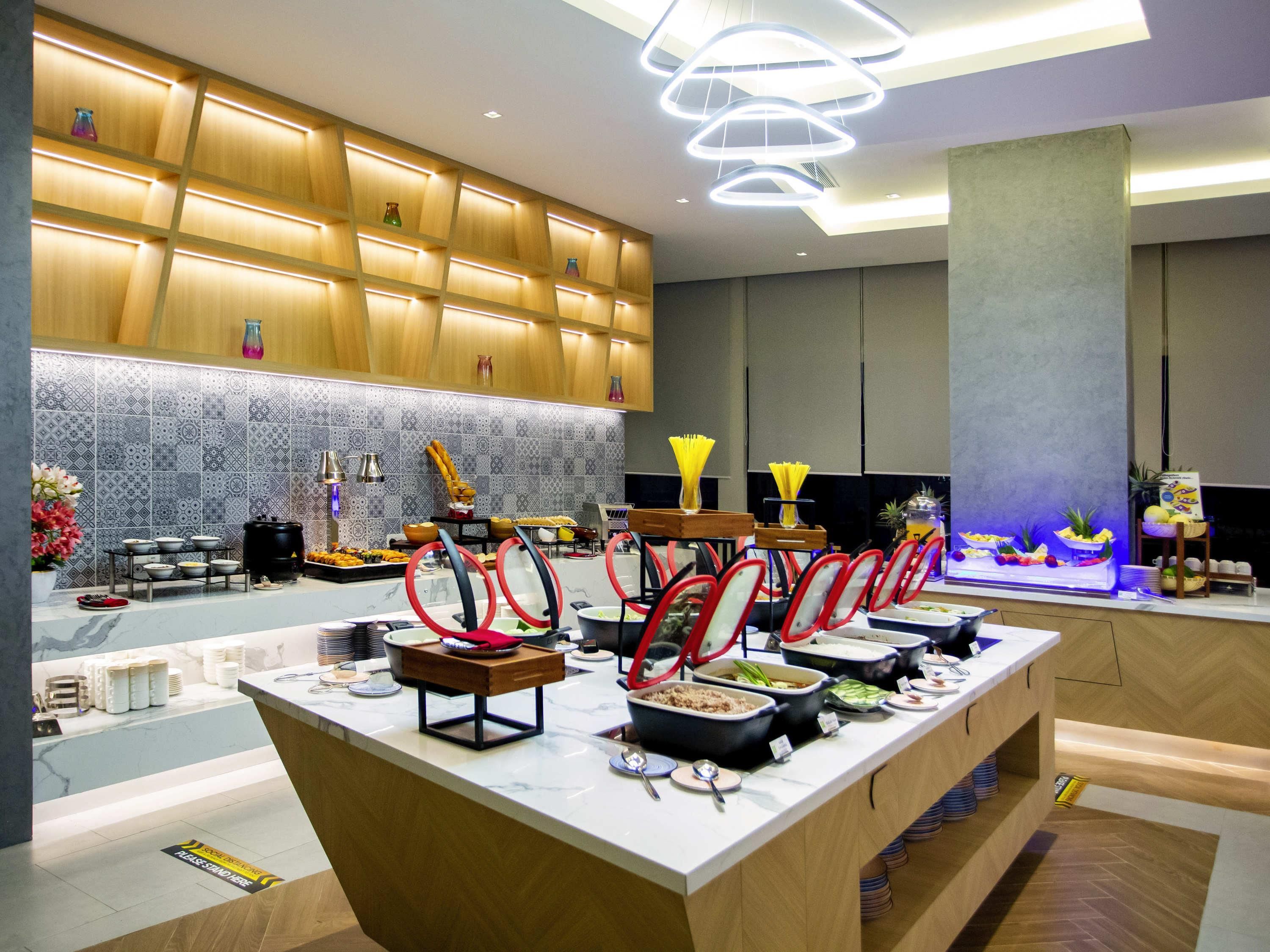 A modern hotel lobby with a buffet area, a reception desk, and a decorative wall with patterned tiles.