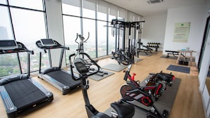 Une salle de sport équipée de tapis de course, de vélos elliptiques et d’un vélo d’appartement.