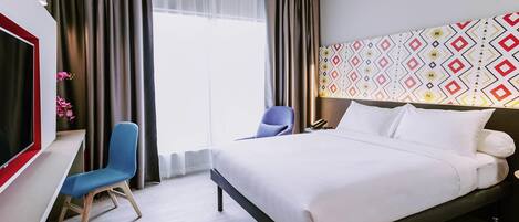 Ein Hotelzimmer mit Bett, Schreibtisch, Stuhl, Fernseher und einer Wand mit Muster.