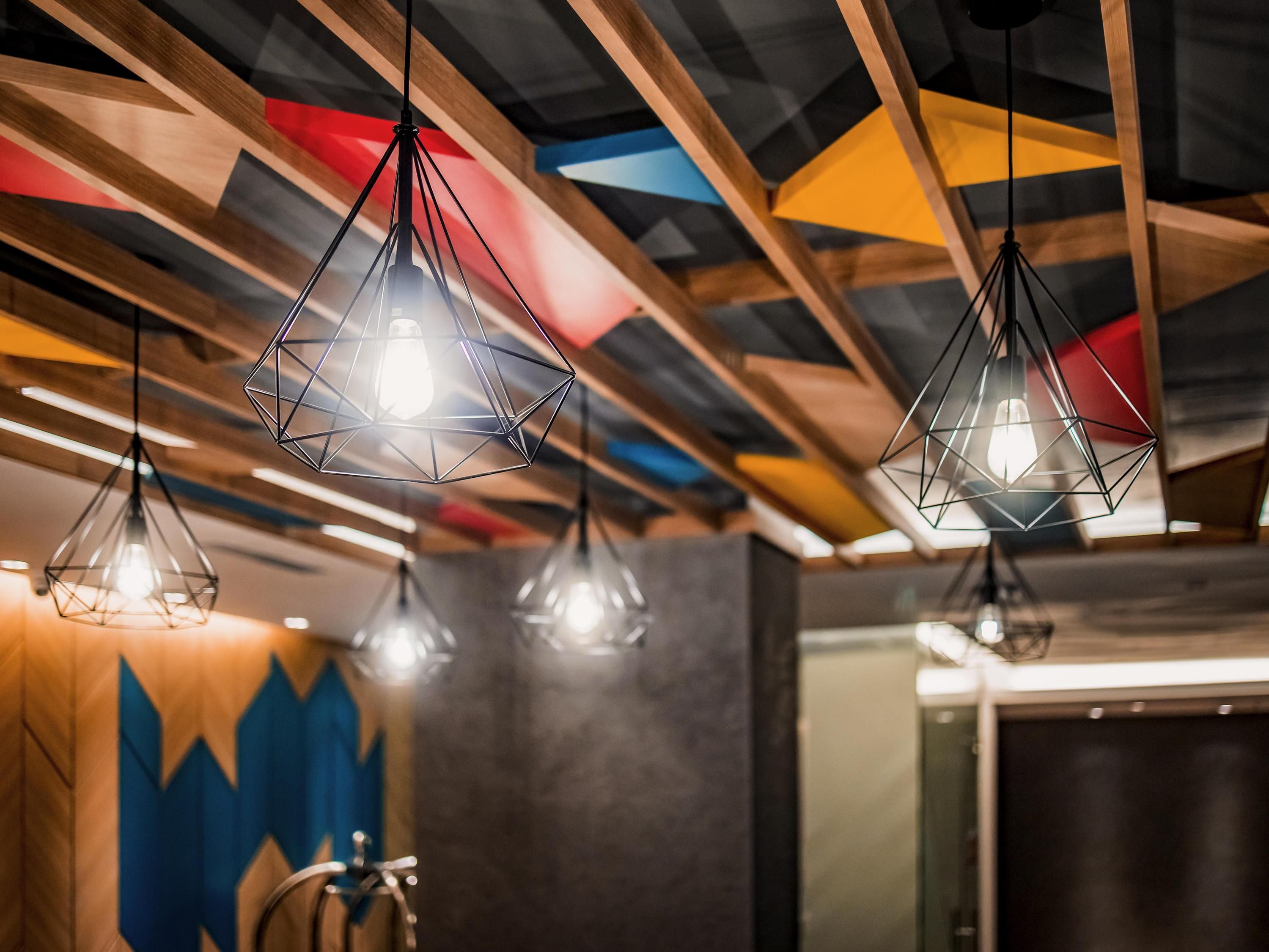 A modern interior with geometric ceiling design and pendant lighting.