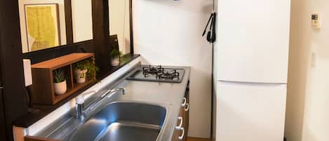 A compact kitchen with a stainless steel sink, a gas stove, and a white refrigerator.