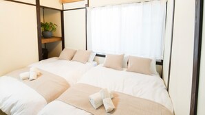 A hotel room with two beds, a potted plant on a shelf, and a window with curtains. - Within walking distance to Shinjuku | 4 min walk to nearest station | Entire 3BR house 75㎡ | Sleeps up to 10 | Family-friendly | High-speed Wi-Fi | Shibuya, Tokyo (Tokyo)