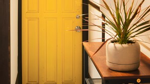 A yellow door with a modern design, a potted plant on a wooden table, and a metal chair. - Within walking distance to Shinjuku | 4 min walk to nearest station | Entire 3BR house 75㎡ | Sleeps up to 10 | Family-friendly | High-speed Wi-Fi | Shibuya, Tokyo (Tokyo)