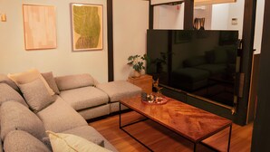 A living room with a sectional sofa, a wooden coffee table, and a large flat-screen TV. - Within walking distance to Shinjuku | 4 min walk to nearest station | Entire 3BR house 75㎡ | Sleeps up to 10 | Family-friendly | High-speed Wi-Fi | Shibuya, Tokyo (Tokyo)