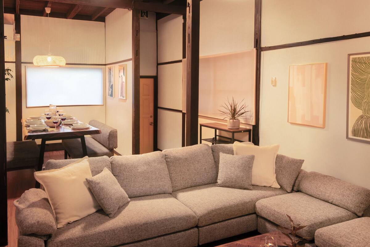 Una sala de estar moderna con un sofá modular, una mesa de comedor con sillas y obras de arte en las paredes.