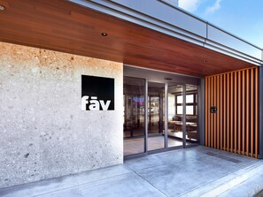 A modern building entrance with a wooden ceiling, a sign with the word 'fäv', and a glass door leading inside. - fav HIDATAKAYAMA (Takayama)