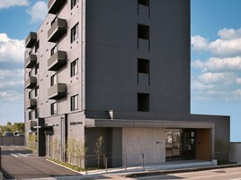 Un hotel moderno con fachada plana, varios balcones y entrada a nivel de calle.