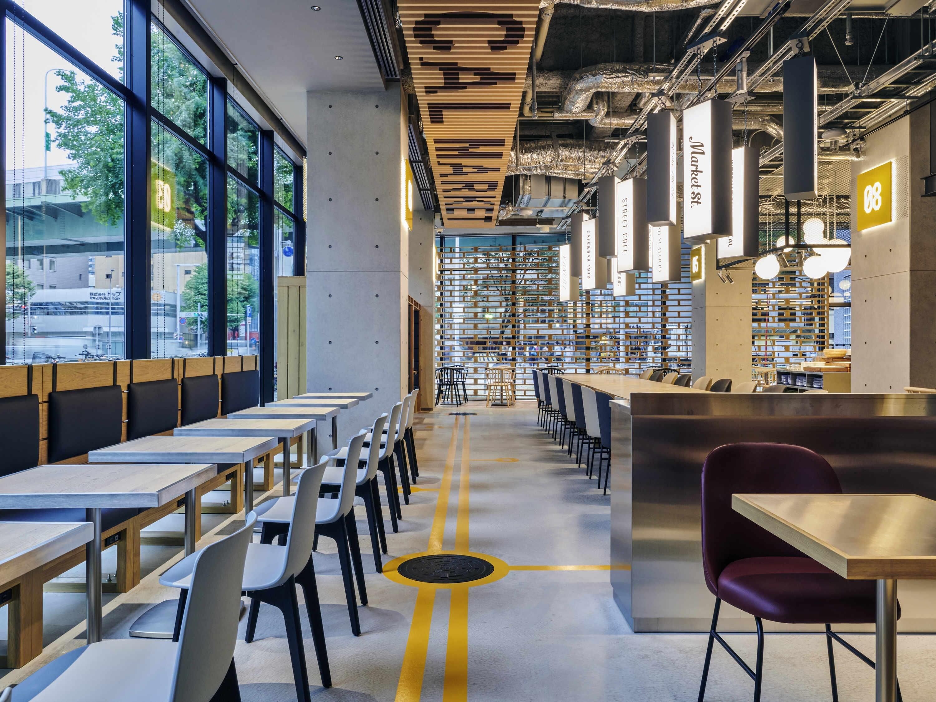 A modern cafe with multiple seating areas, including tables and chairs, and a central counter.