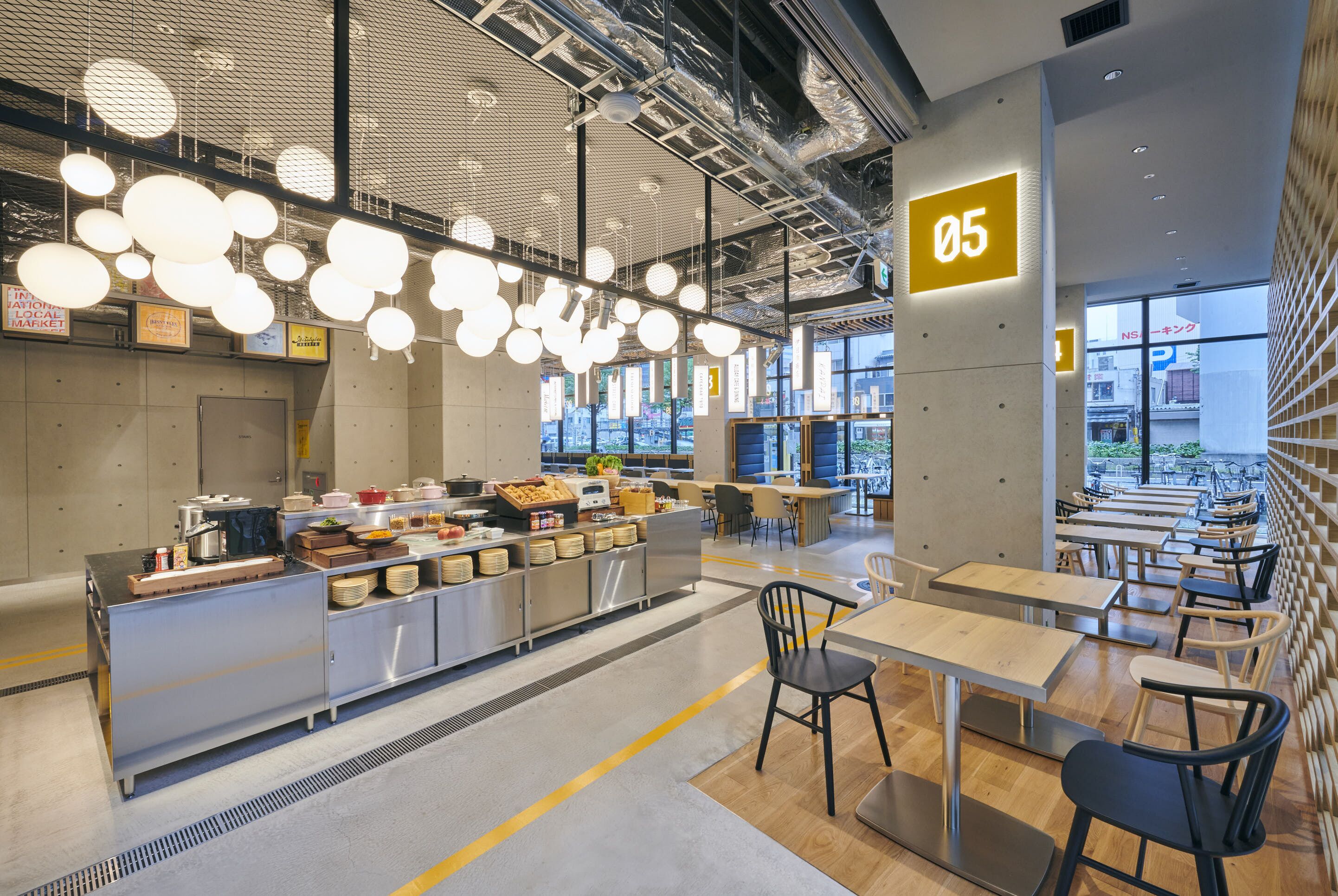 Una cafetería moderna con una estación central de servicio, varias mesas y sillas.