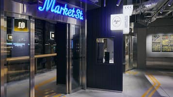 A modern interior with a neon sign reading "Market St." and a sign indicating "International Local Market."