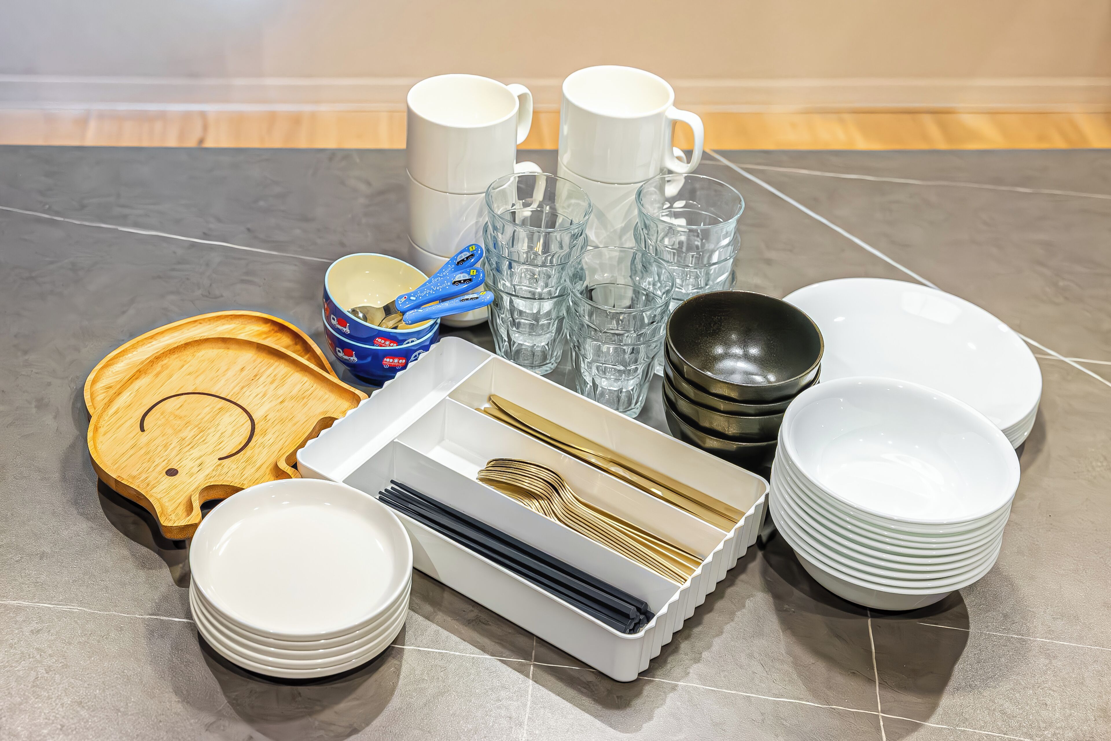 A neatly arranged table with various dining items including plates, bowls, cups, and cutlery.
