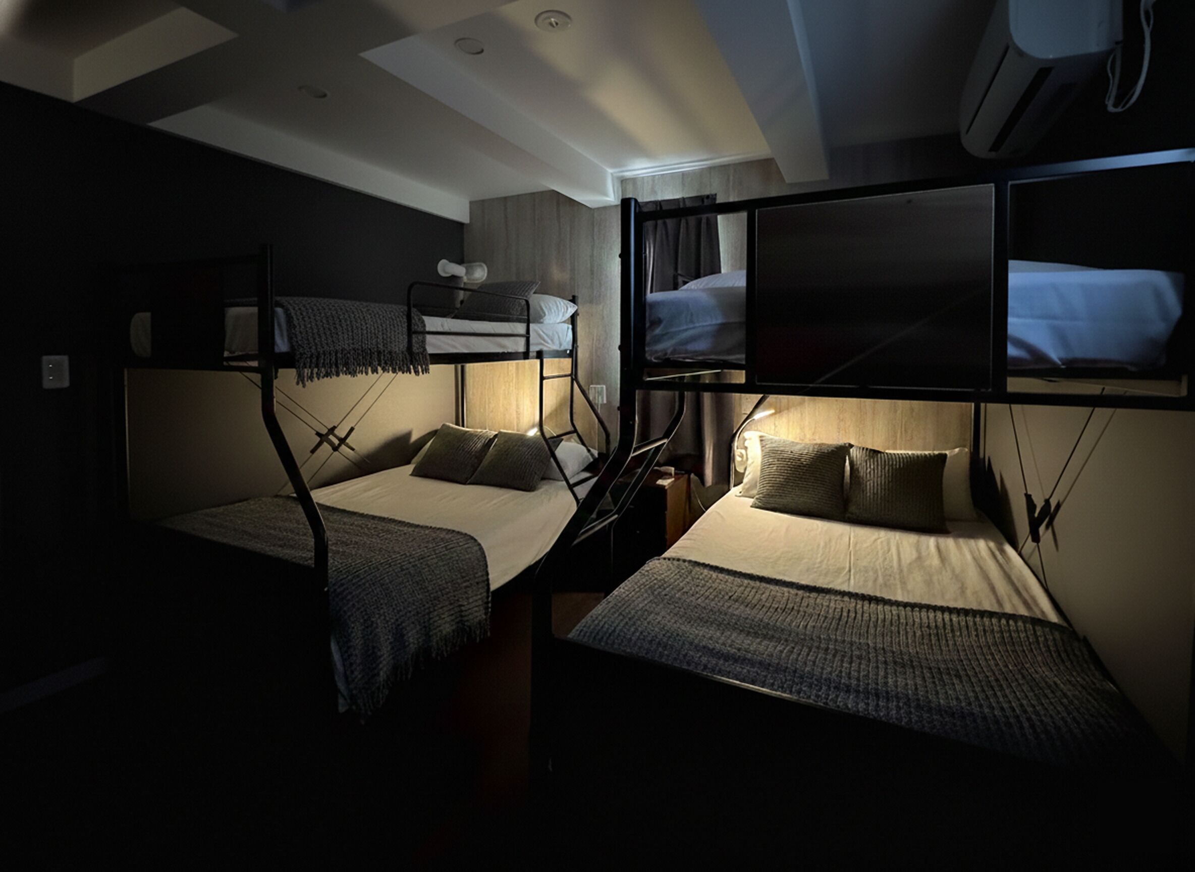 A compact hotel room with bunk beds, a television, and a ceiling fan.