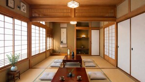A traditional Japanese room with tatami flooring, a central wooden table, sliding doors, and a ceiling fan.