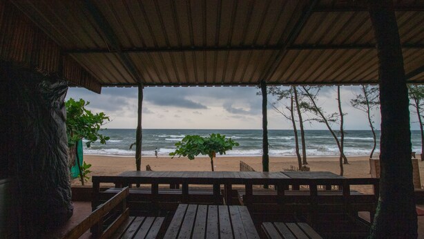 Una terraza de madera con bancos que da a una playa y al océano.