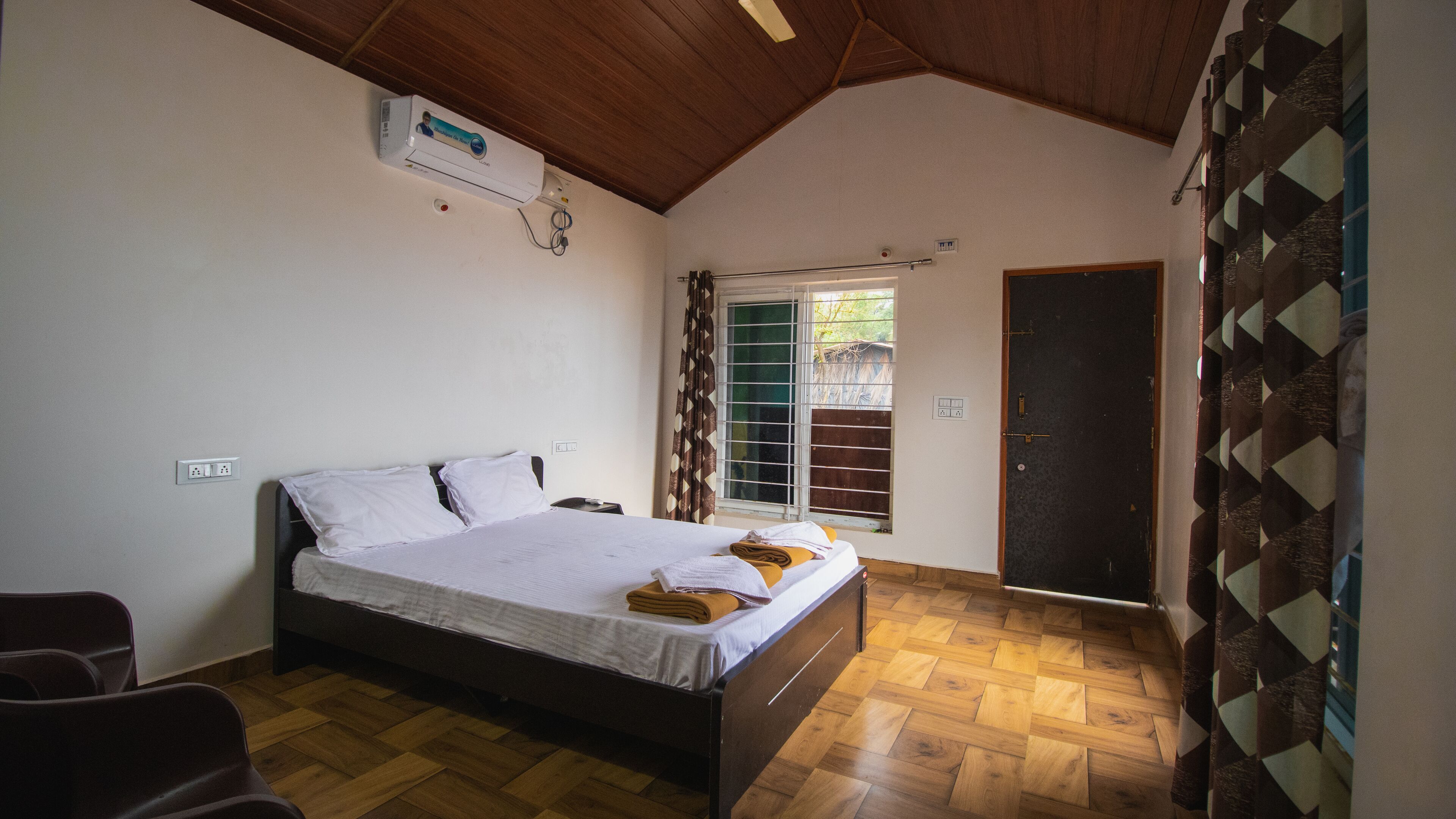 A bedroom with a bed, a heater, a window with a view, and a door.