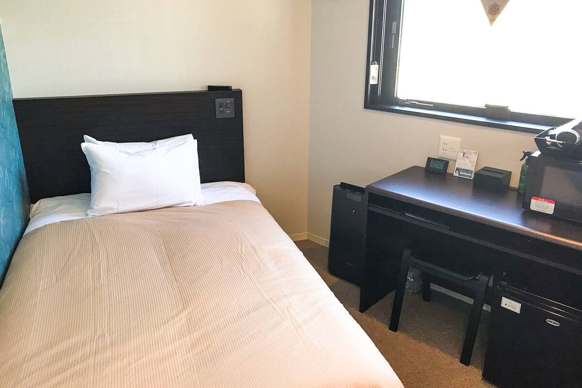 Une chambre d’hôtel avec un lit, un bureau et une fenêtre.