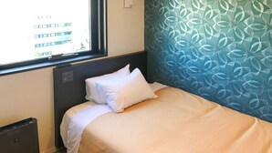A hotel room with a bed, a window, a radiator, and a patterned wall. - Hotel Livemax Ikebukuroekimae (Tokyo)