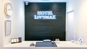 A hotel reception desk with a 'HOTEL LIVEMAX' sign, a clock, and a security camera. - Hotel Livemax Ikebukuroekimae (Tokyo)