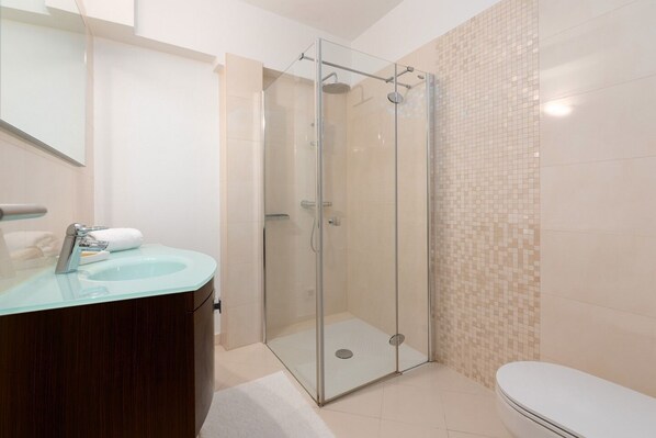 Une salle de bain moderne avec une douche à parois de verre, un meuble-lavabo en bois et des toilettes.