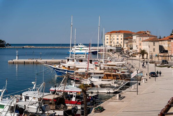 A marina with boats docked, a pier, and buildings in the background. - Bellevue Designer Apartment (Porec)