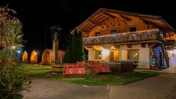 Ein zweistöckiges Holzhaus mit Balkon, Whirlpool und einer Treppe, die zu einer oberen Ebene führt.