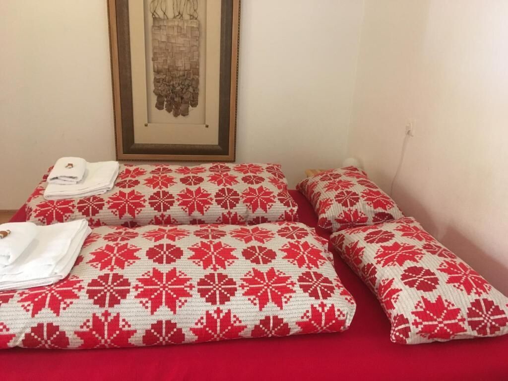 Un lit avec des oreillers à motifs rouges et blancs et une serviette blanche posée sur le côté.